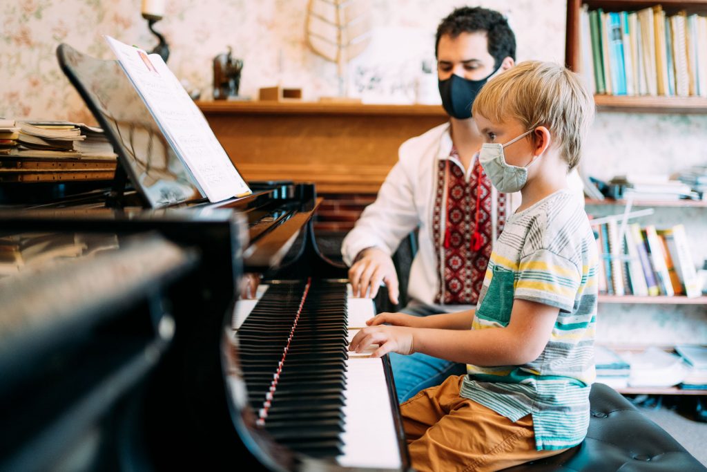 A boy with a teacher playing the piano
